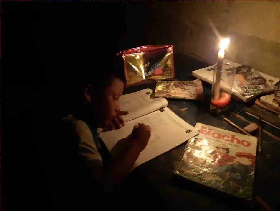 Un niño estudiando a la luz de la vela
