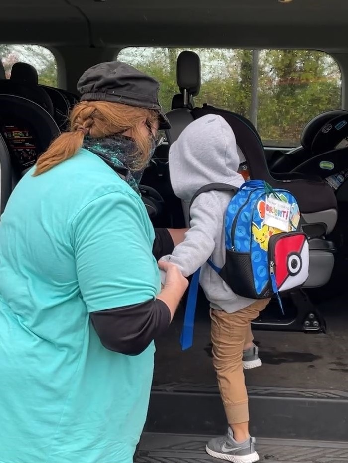 Dial-A-Bus driver helping a child into a Dial-A-Bus vehicle to take him back home.