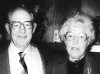 Elderly man and woman with glasses smiling at camera