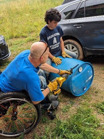 A person in a wheelchair using a tool to remove a barrel 
Description automatically generated