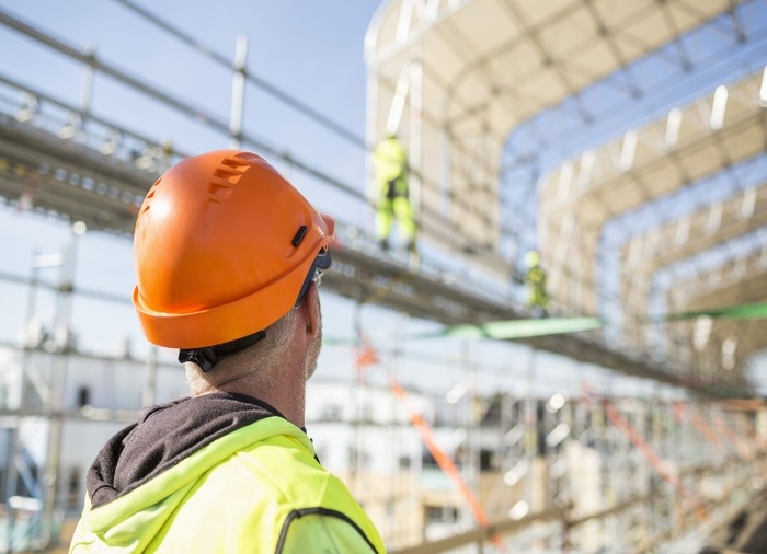 Worker with protective gear looking up at construction site