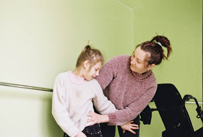 Sophia (9) who has cerebral palsy and her mother Olia (29) play in the hallway of the Dzherelo Centre as Olia helps Sophia stand for a portrait (Emma Francis)