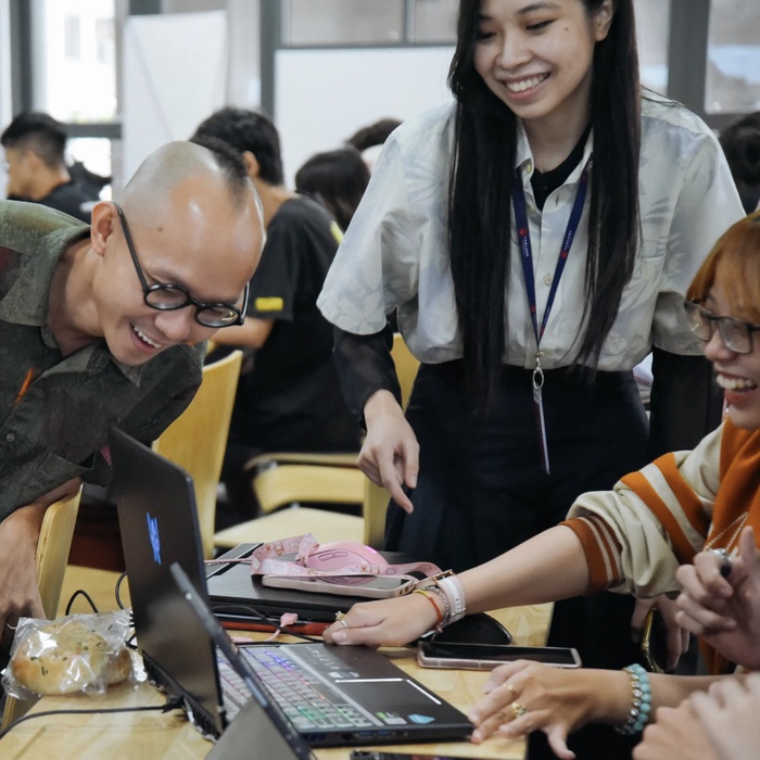 A photo of Processing Foundation Fellow Nhan Phan and his students. Students and teachers are joyfully gathered around a computer.