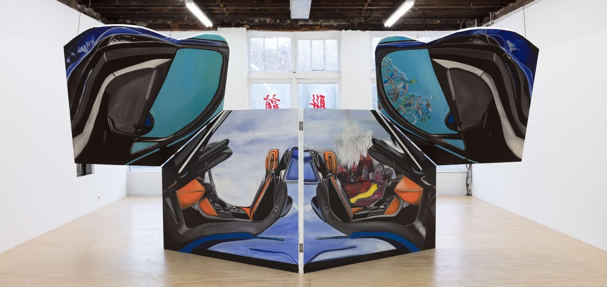 A massive sculpture assembled from painted elements of a car in a gallery.