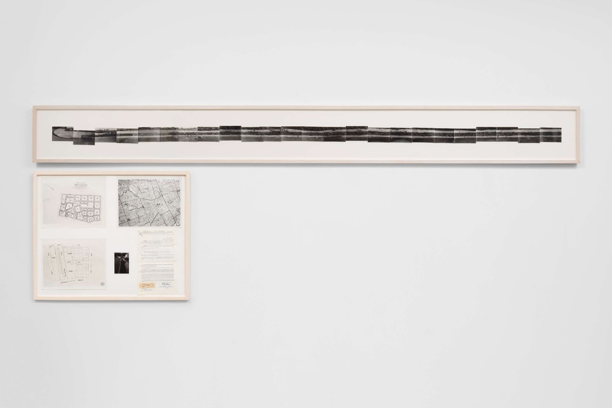 A long, thin, horizontal artwork of a sidewalk, created by multiple small black & white images. Under, an artwork with maps and construction plans.