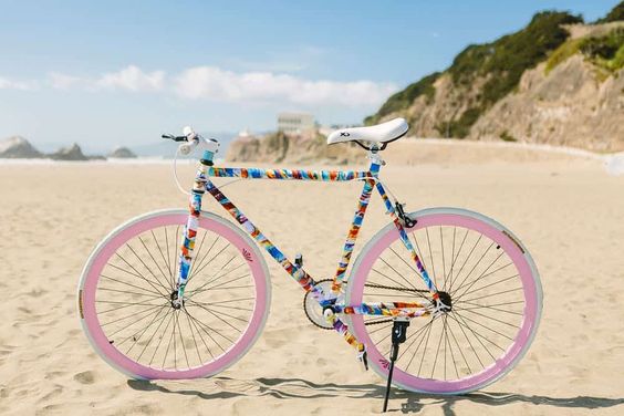 funky bike with pink wheel on beach