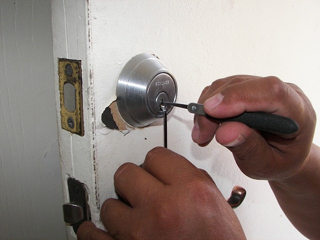 A locksmith trying to pick a lock of a door.