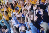 A large group of PSD staff members smile and wave their hands in the air.