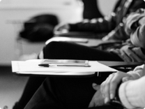 Black and White photo of students sitting at desks with pen and paper