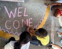 student writing welcome in chalk on ground