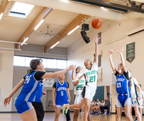 Middle school girls playing basketball and jumping for the ball