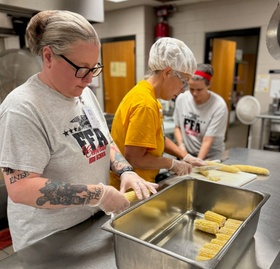 3 cafeteria workers preparing corn