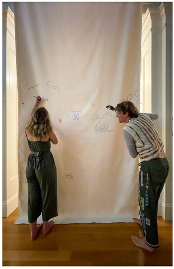 Two people drawing on a canvas falling from the ceiling.