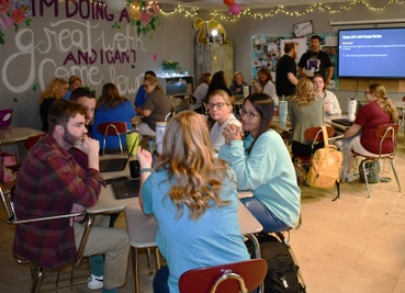 Groups of people sitting in desks that are pulled together in classroom