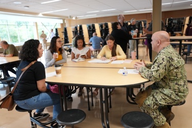 A group of volunteers and Oak Harbor Public Schools staff discussing volunteer opportunities at a school cafeteria table