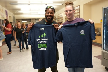 staff members hold up t-shirts for the new strategic plan