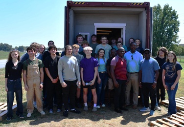 Group photo of a class that worked on project in front of container