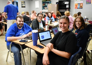 four people at desks pose for photo