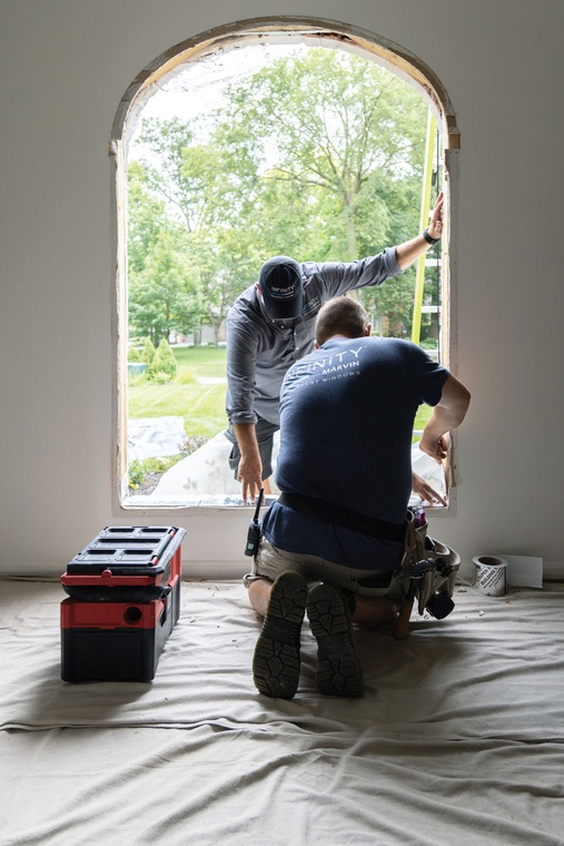 Window installers work to prepare a rough opening for a new window.