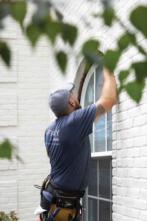 An Infinity from Marvin window installer places a single hung round top window into a frame.