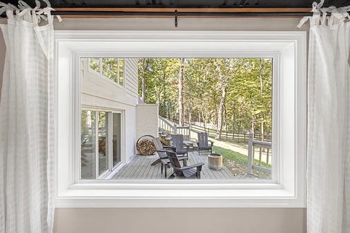 Interior view of a white picture window in a bedroom looking out to a deck.