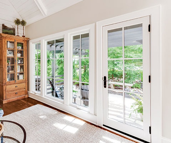 Interior image of a living room featuring a swinging Frnch door, casement and picture windows in stone white finish