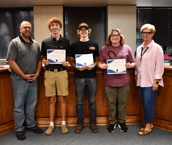 5 people pose for photo with 3 holding certificates