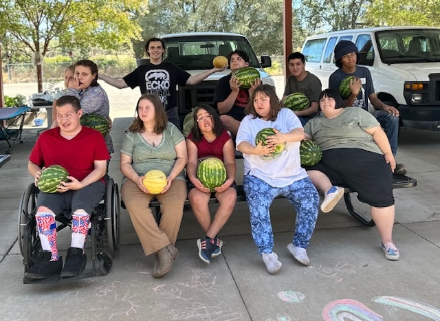 A group of students pose for a photo holding freshly-picked watermelon