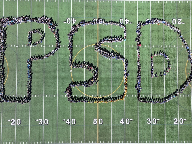 An aerial photo of the football field at Peninsula High School with a large "PSD" spelled out by PSD staff members standing together in the shape of the letters.