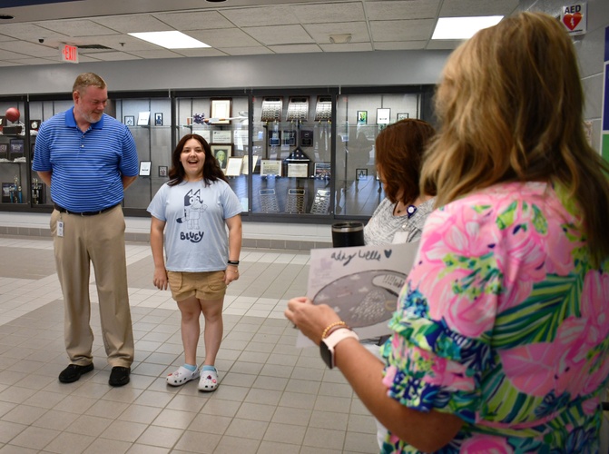 2 people stand looking at 2 others, with one holding a drawing