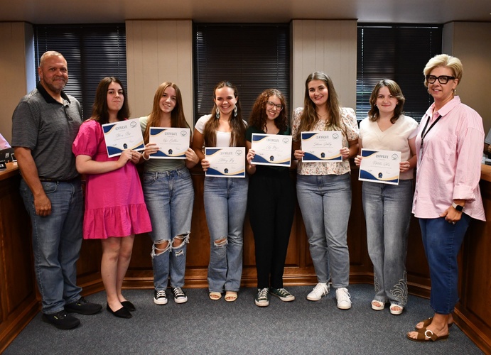 8 people pose for photo with 6 holding certificates