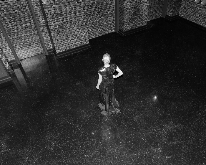 Black and white photograph looking down on a woman in a black gown from above.