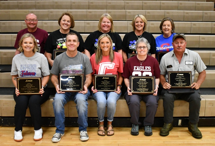 10 people sit on bleachers in 2 rows holding plaques