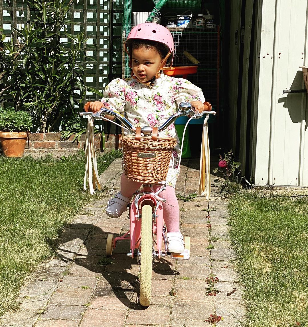 Kleinkind auf rosa Fahrrad mit Lenkerquasten
