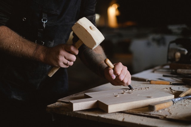 A man using tools to carve a cutting board