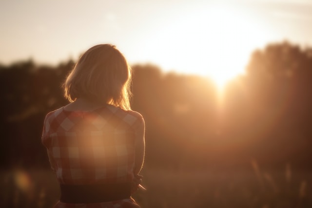 A girl, sitting alone watching the sunrise while thinking about couple's problem.