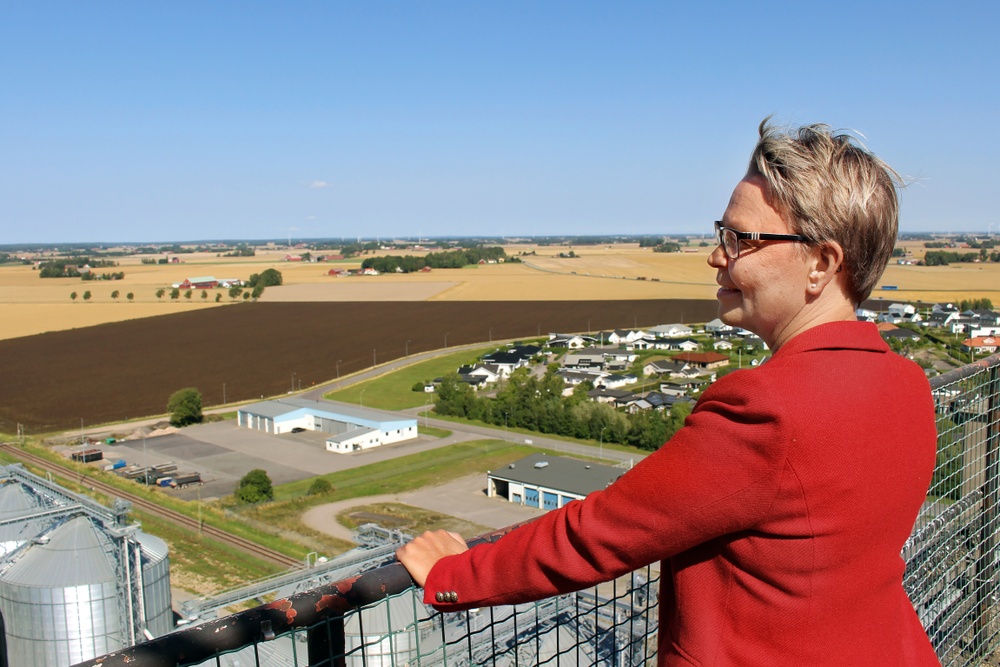 En bild på Vara kommuns kommundirektör Anna Cederqvist. Fotot är tagen på en hög byggnad och hon tittar ut över slätten.