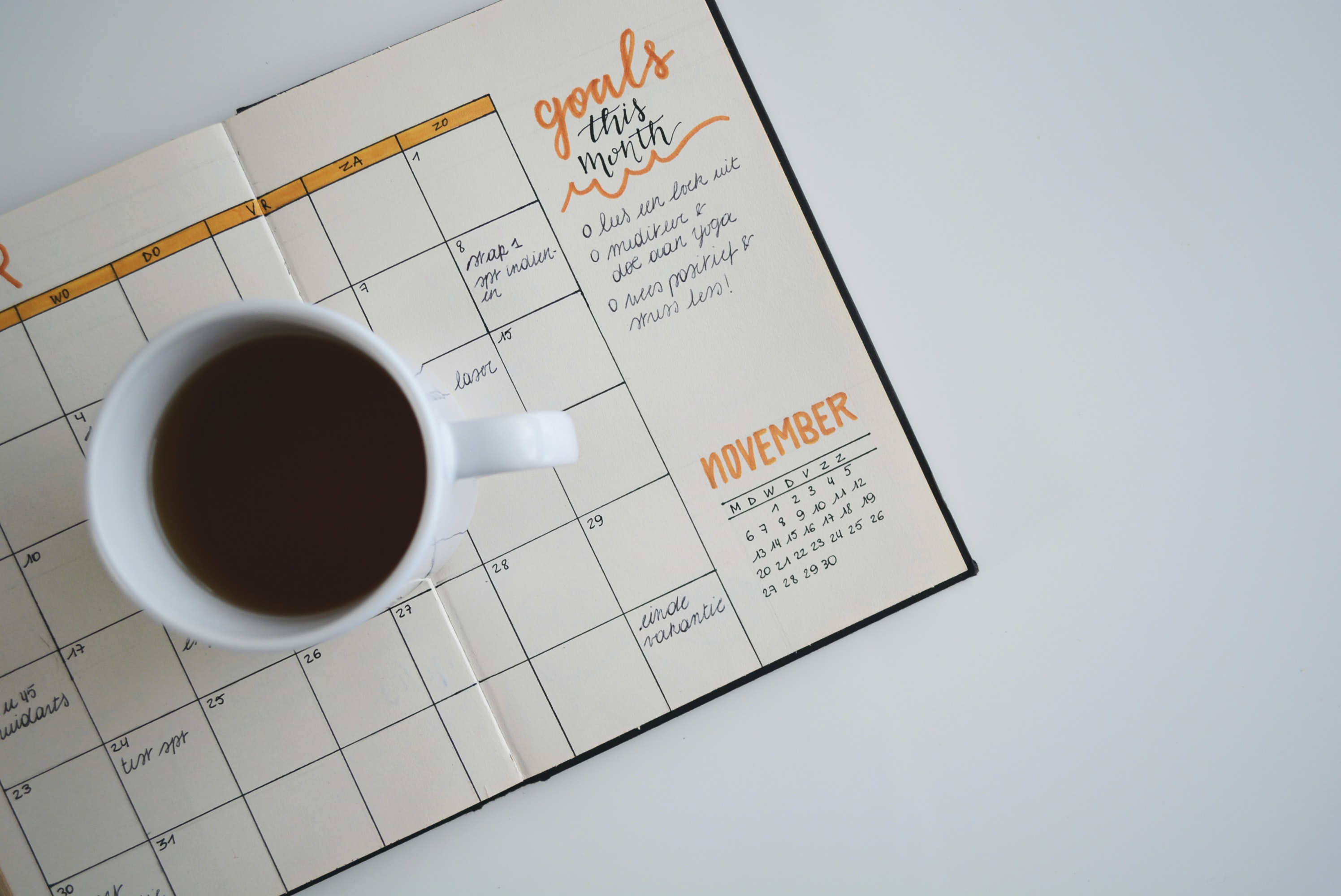 A mug placed on a calendar showing the goals for the month