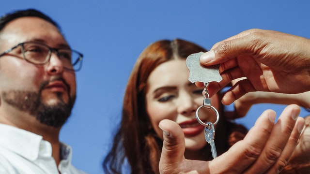 a couple receiving a key to a house for rent