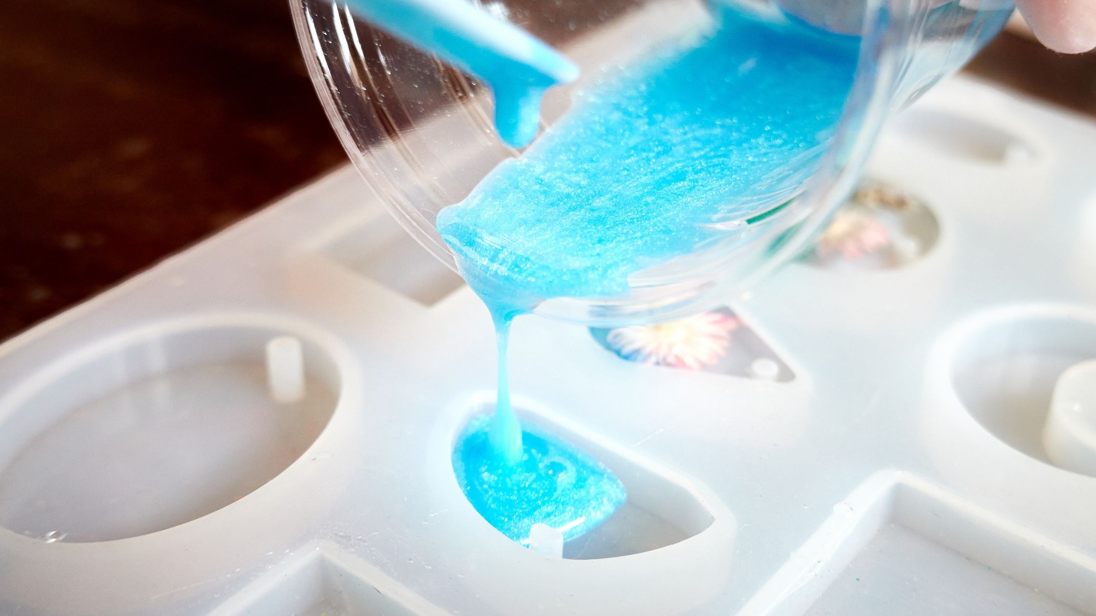 blue colored epoxy resin being poured into a mould