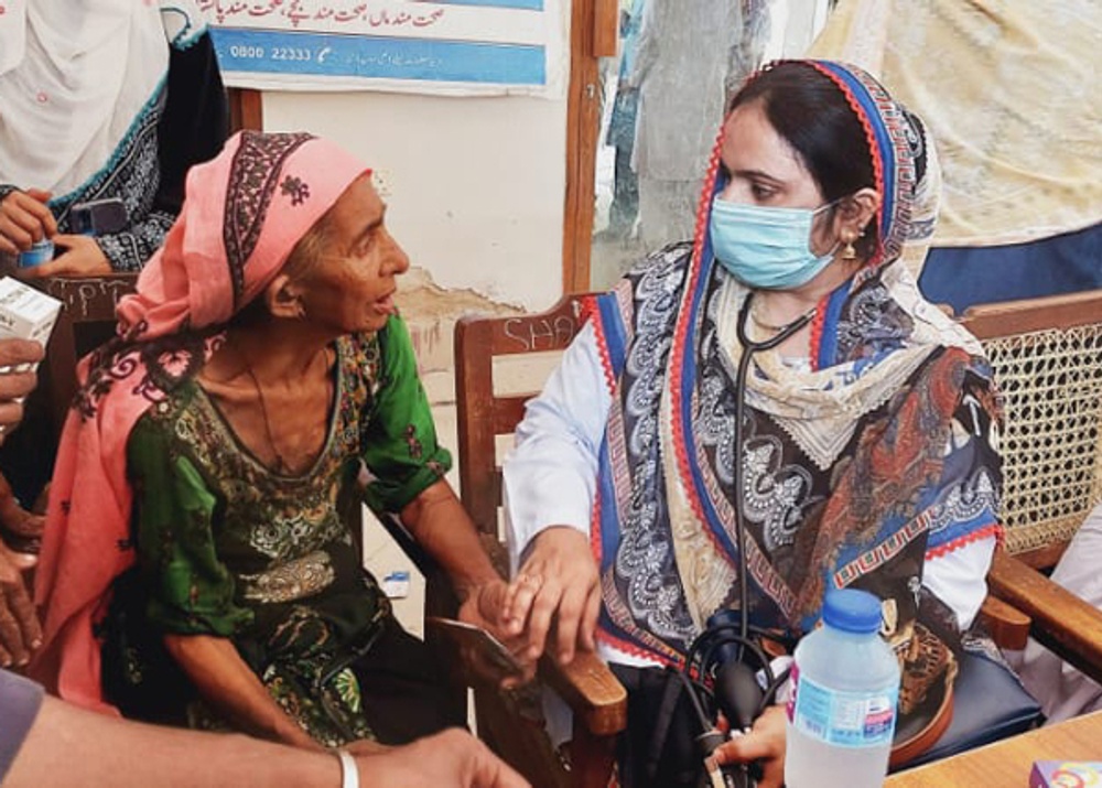 Den lokala sjuksköterskan Tahmina möter kvinnor och flickor som bor i läger i Dadu. Här är hon med en patient vid ett gratis vårdläger vid Behtar Zindagi Centre i Dadu, Sindh, Pakistan. WaterAid/ Khaula Jamil.