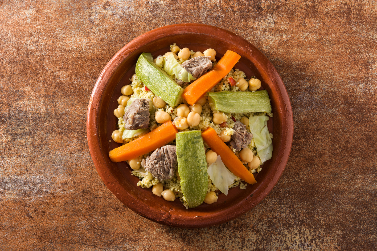 Couscous in a traditional pot, chickpeas, zucchini, carrots and meat