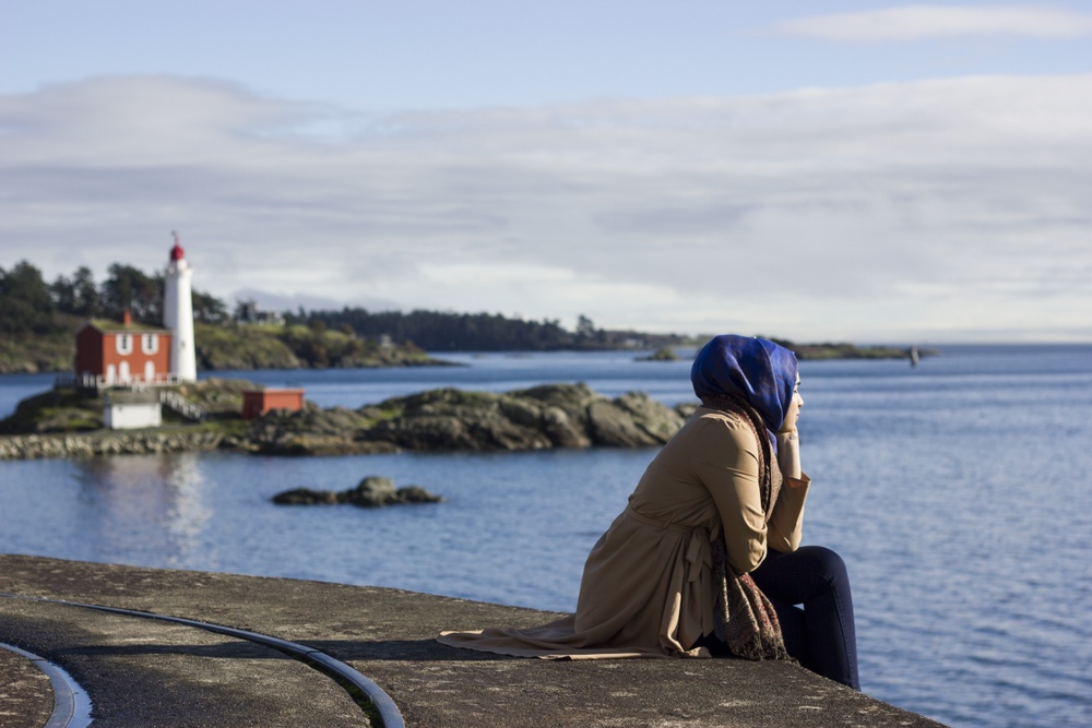 Ung kvinna med hijab blickar ut över en sjö