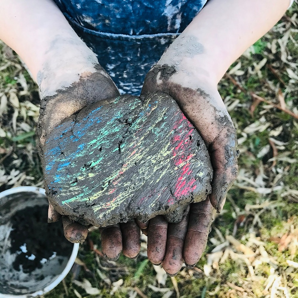 Child holding a colourful piece of mud