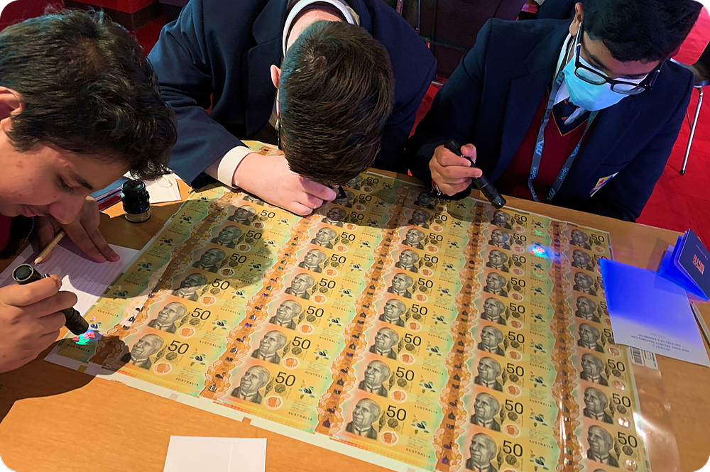 Students discovering secret UV features on a sheet of banknotes